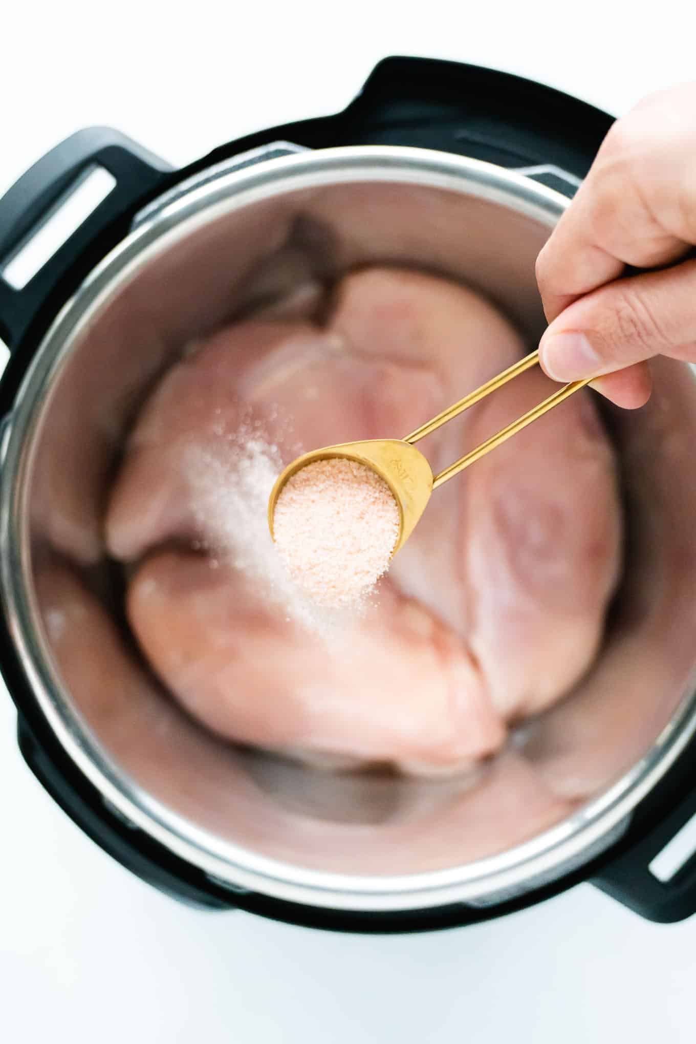 Sprinkling salt onto chicken with a teaspoon