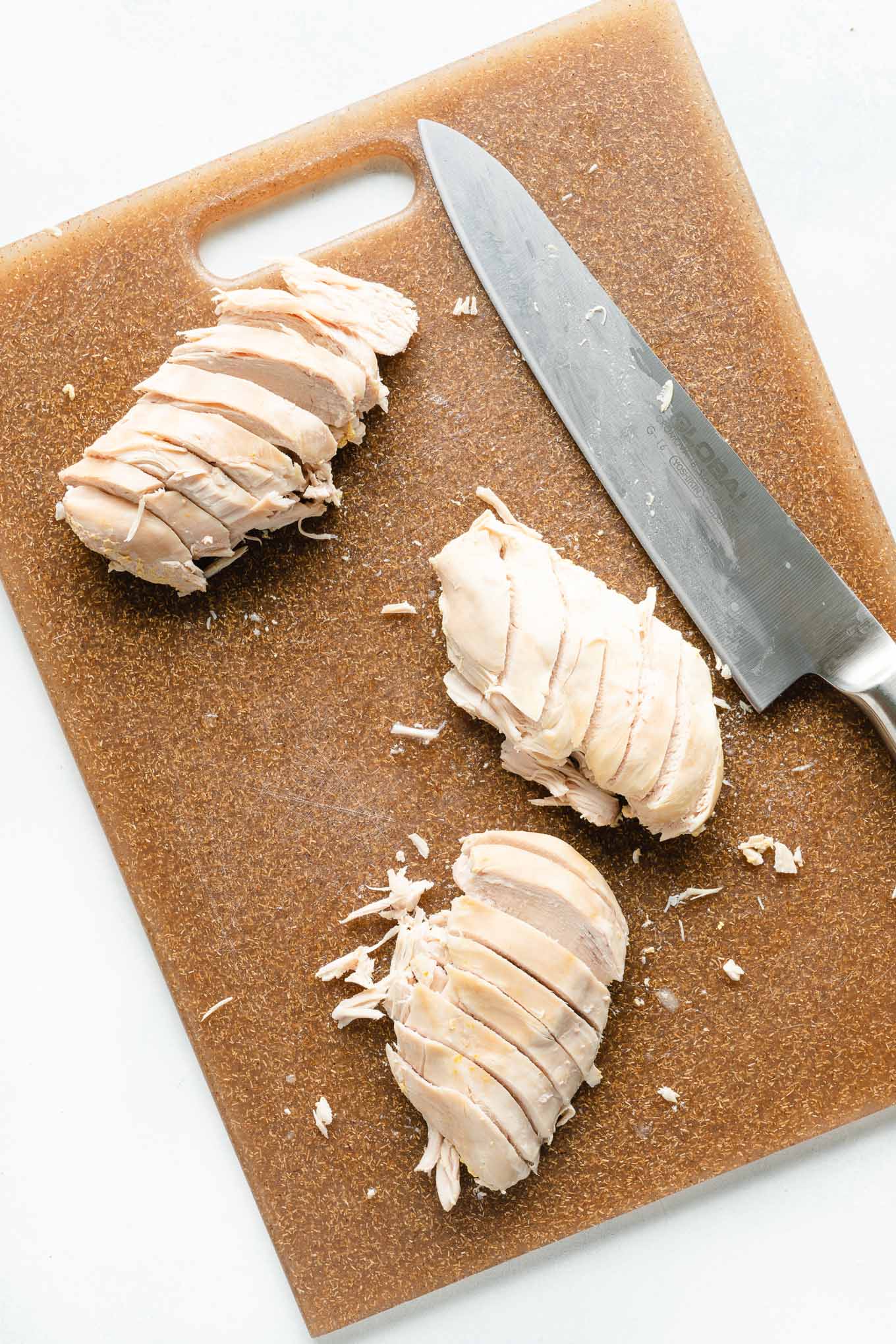 Chicken breast sliced on brown cutting board