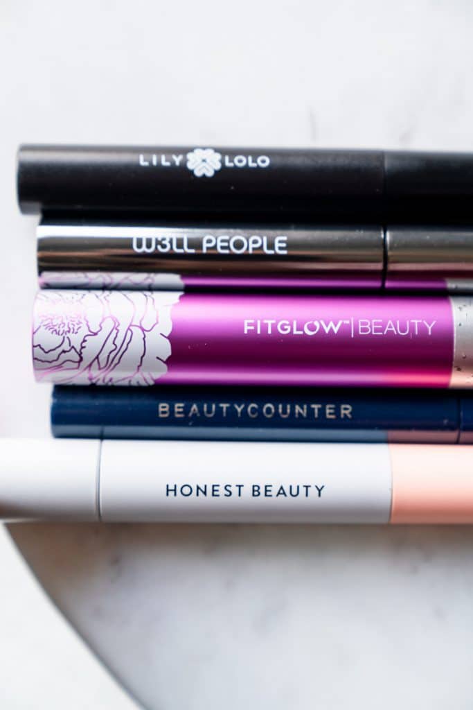 five of best safer mascaras tubes laying on a white table